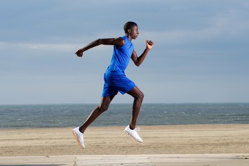 Fototapeta premium Fit young african man running along the beach