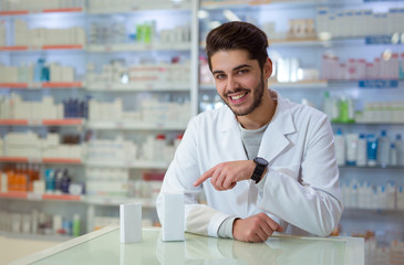 Fototapeta na wymiar Friendly male pharmacist dispensing medicine holding a box of tablet