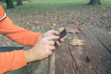 Man using cellphone on a bench in the park.