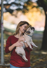 People and dogs outdoors. Portrait of beautiful and happy woman enjoying in autumn park walking with her adorable French bulldog.