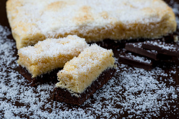 Homemade cake with coconut and chocolate layers on black background