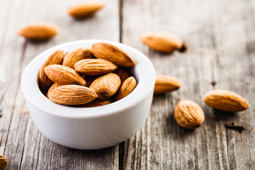 almonds in ceramic bowl on wooden background