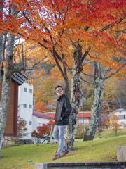 a man relaxing with a beautiful Japan , Nikko autumn tree . focus on the model . Japan autumn set