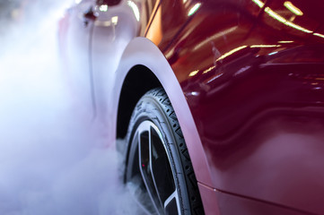 Close up of red car's wheel with smoke, fog around it.