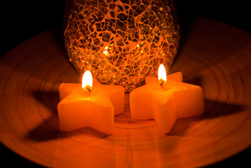 Brennende Sternkerzen vor Mosaik 