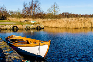 Small open motorboat moored beside stone pier in lovely fall coastal landscape. Location Blekinge in southern Sweden.