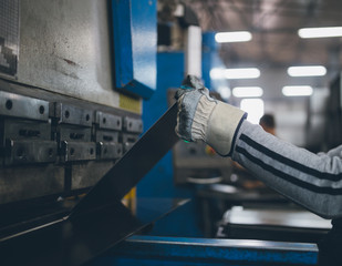 Metallurgy heavy industry. Factory for production of heavy pellet stoves and boilers. Line for steel profile and plate cutting. Extremely dark conditions and visible noise. Focus on foreground.