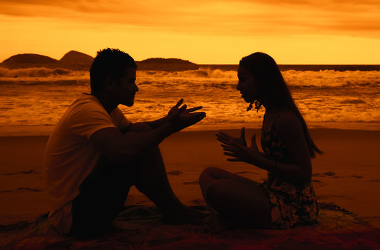 Paar diskutiert am Strand bei Sonnenuntergang