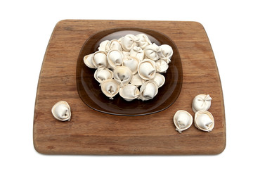 Russian dumplings in a plate on a chopping board.