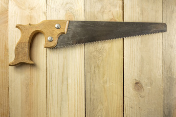 Vintage hand saw on wooden background with copyspace