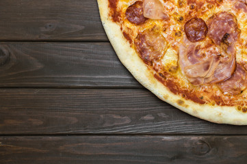 Close up of slice of fresh pizza on dark brown table background with copy space to write your text.