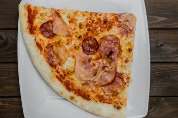 Slice of fresh pizza on dark brown table background, close up