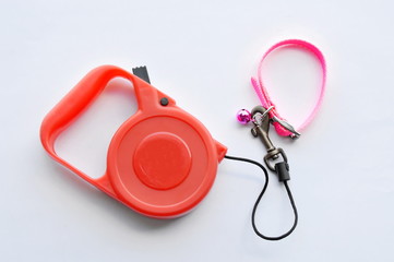 red automatic leash and pink nylon cat collar on white background