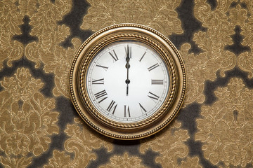 Luxurious clock with roman numbers on the wall with beautiful wallpaper in the New Year midnight....
