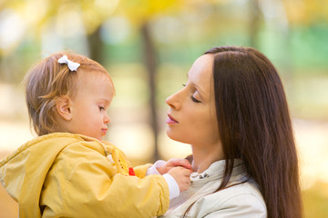 Mother and child playing with leaves in autumn park