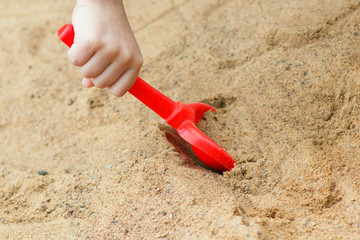Fototapeta na wymiar shovel in hand the child in a sandbox
