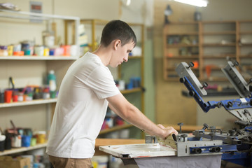 Young confident, experienced male working with squeegee on a small factory, handsome worker man...