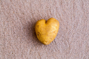 Heart shaped potato on white table background