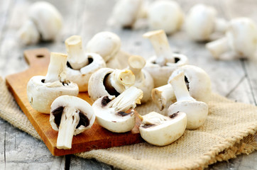 Slicing champignons on a wooden chopping board and sackcloth