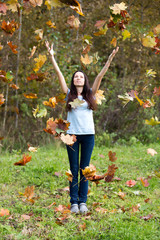 Beautiful young girl in the falling autumn leaves