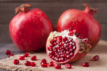 Obraz na płótnie Canvas two pomegranate on the old wooden board with sackcloth