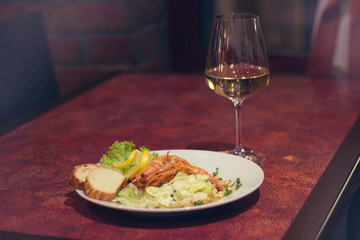Restaurant food with fresh ingredients - giant shrimps with freshs salad and glass of white wine