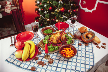 Christmas dinner by candlelight, table setting. Thanksgiving table with baked turkey in a decorated room with a Christmas tree.