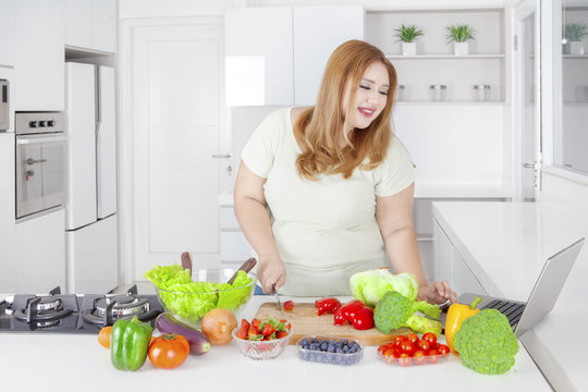 Obese woman cutting paprika