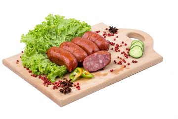 Smoked sausages on a kitchen wooden board on white background