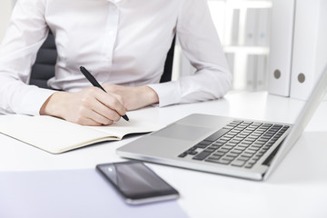 Front view of girl in white shirt typing and writing