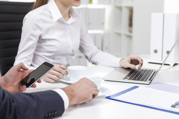 Close up of woman in white blouse and her coworker in office