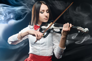 Dreamy woman playing the violin on a black background