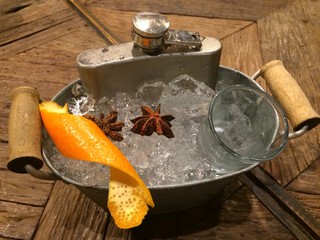 Hip screwdriver cocktail in the flask severing on the ice bucket decorate with orange skin and star anise on the wood table