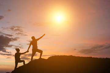 Fototapeta premium Mountaineer gives helping hand to another people while climbing up on sunset. Concept mountaineering