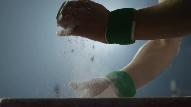 Sportsman chalking his hands before performance . Shot on RED EPIC Cinema Camera in slow motion.