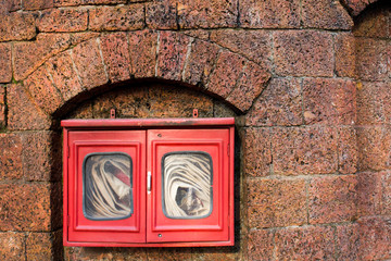 Fire hose in red box on brick wall background