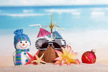Coconut in the sand with umbrellas and snowman, starfish, a Christmas ball