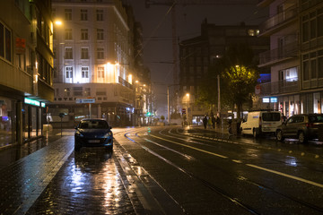 Fototapeta na wymiar Night rainy street in Ostend, BelgiuFence around playground, Ostend, Belgium