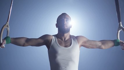 Gymnast performing gymnastic cross exercise on gymnastic rings. Shot on RED EPIC Cinema Camera in slow motion. - Powered by Adobe