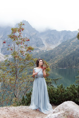 beautiful sweet girl bride in her wedding dress light air in the mountains near the lake, a beautiful landscape of mountains