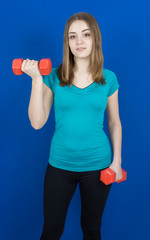Fototapeta na wymiar girl with dumpbells on blue background sport concept gym