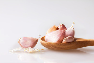 Close up garlic in a wooden spoon on white background