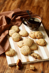 Chocolate Chip Cookies, cup of coffee on light wooden board and dark wooden background.