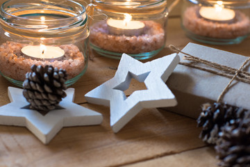 Gift box, scattered pine cone, tea lights in jars with himalaya salt, wood decoration stars, Christmas, New Year, advent