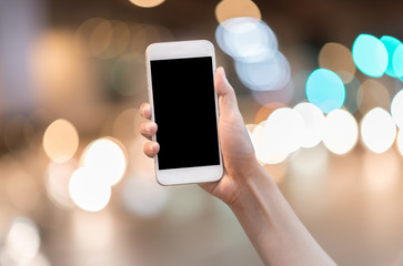 Hand holding blank screen smartphone mobile on abstract blurred city light bokeh background