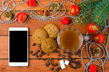 Smartphone and Christmas decorations on a wooden table.