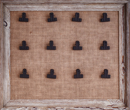 Notice board with hessian backing and twelve clips for holding notes, framed in a distessed wood