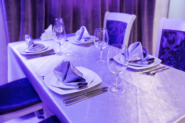 Empty glasses and dishes set in an interior new luxury restaurant with covered tables