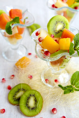 Fruit desserts, salad of pineapple, papaya, pomegranate and mint, kiwi on light background