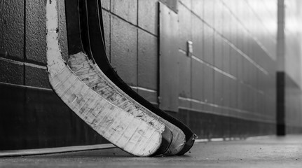 Black and white macro shot of hockey stick blades laid on a dirty arena floor - Shallow depth of...
